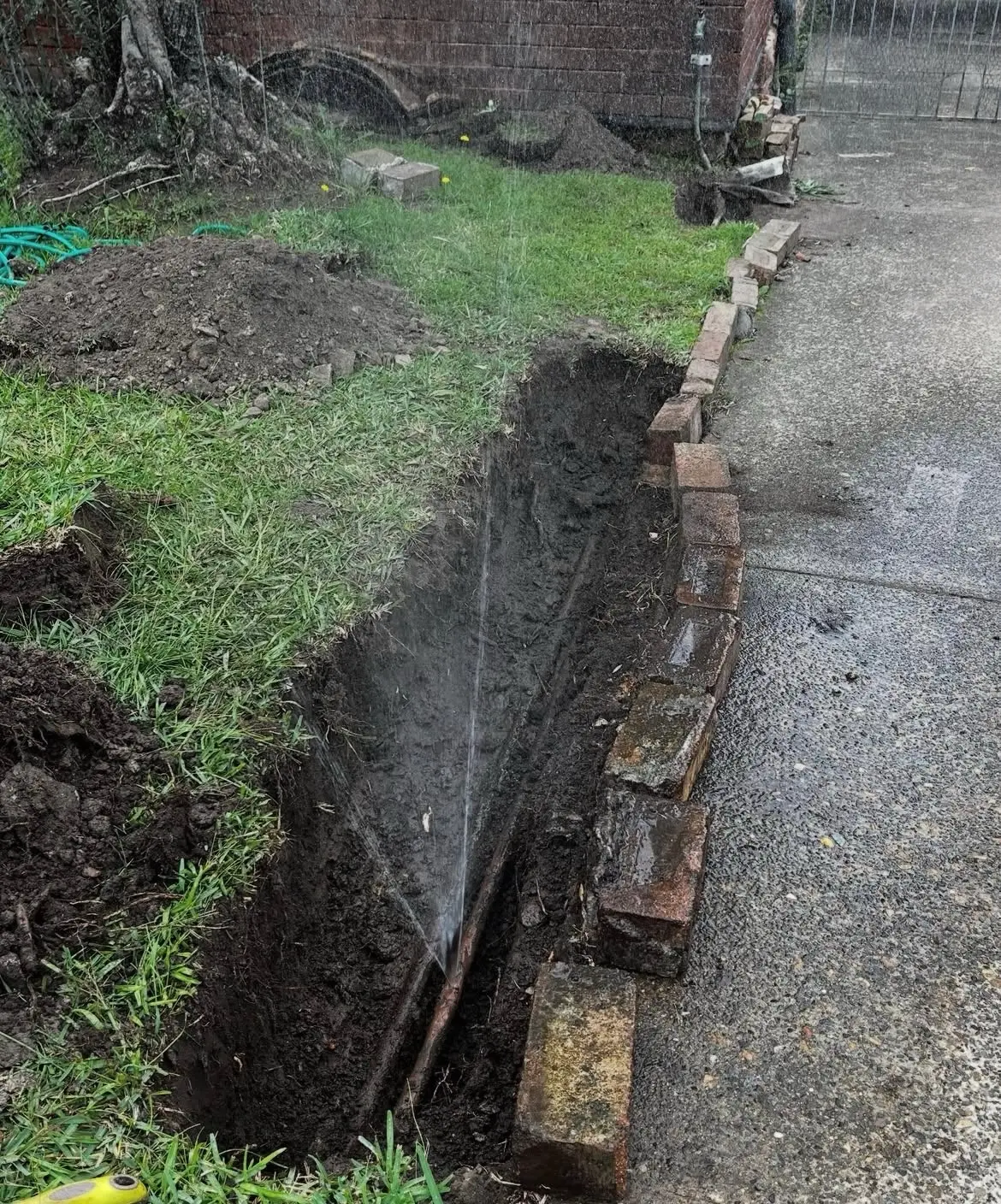 Burst underground water pipe spraying in an excavated trench